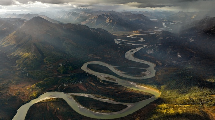 Meandering river through mountains under dramatic sky