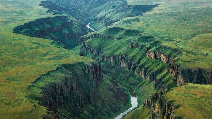 Green canyon with a river and grassy plains