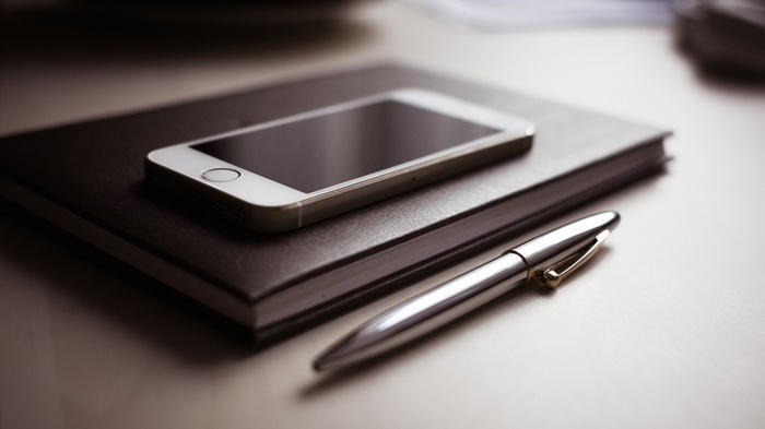 iPhone on a notebook with a pen