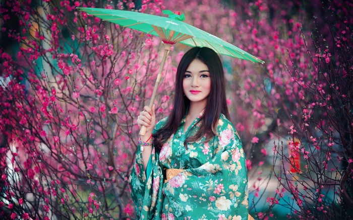 Woman in traditional green floral kimono holding a parasol