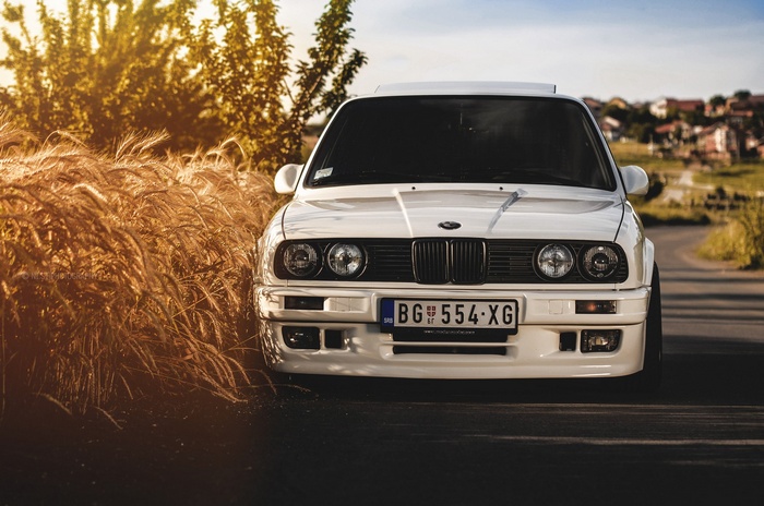 White BMW E30 parked by a field