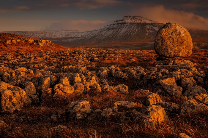 Balanced rock on a rocky landscape with snow-capped mountains