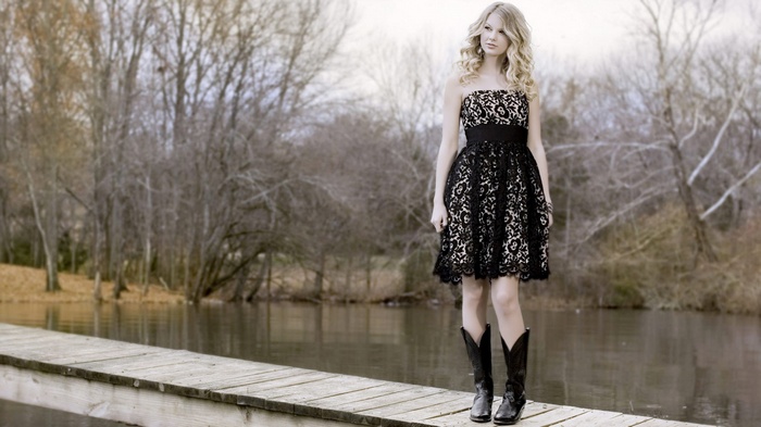 Taylor Swift in a black dress and cowboy boots