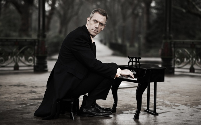 Hugh Laurie plays a miniature piano in a park