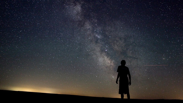 Silhouette of a person under the Milky Way galaxy