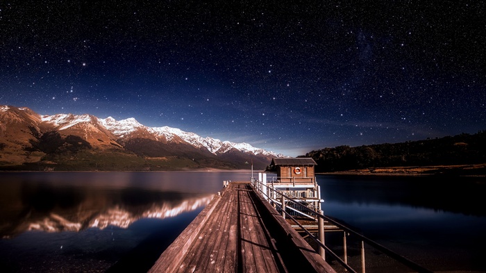 Wooden pier with a small cabin under a starry sky