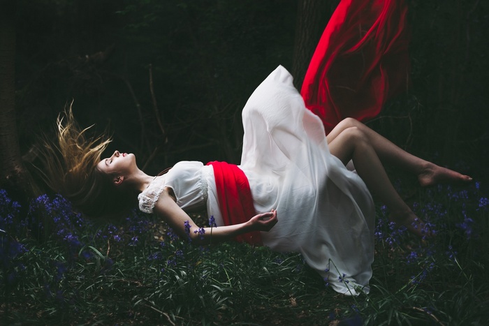 Woman in white dress floating in forest