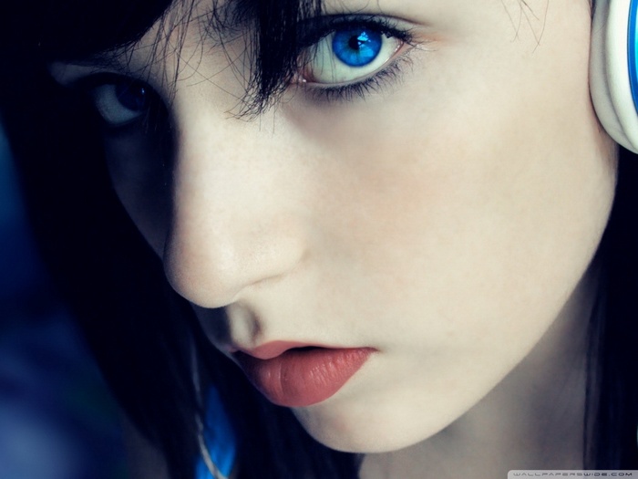 Close-up of a young woman with blue eyes wearing headphones
