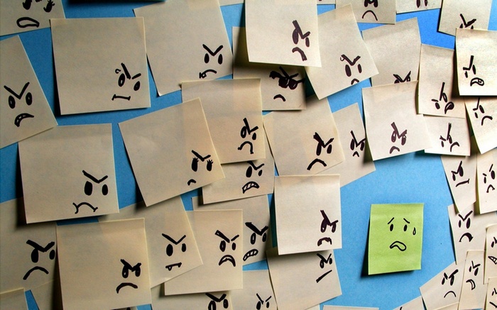 Angry faces on sticky notes with one sad face
