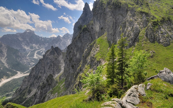 Jagged mountain peaks and green slopes under a cloudy sky