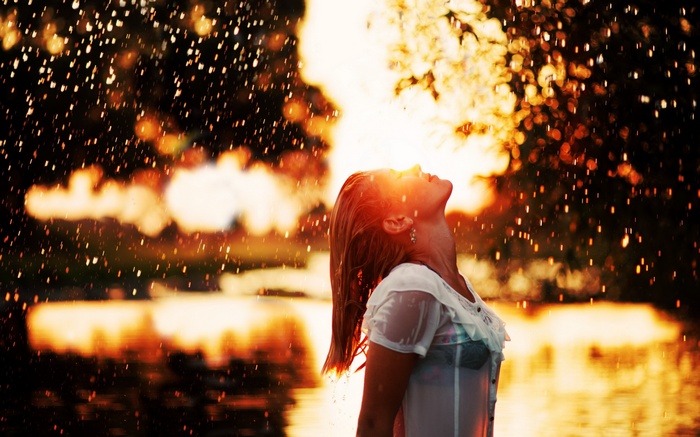 Woman in wet clothing looking up at golden hour sunlight