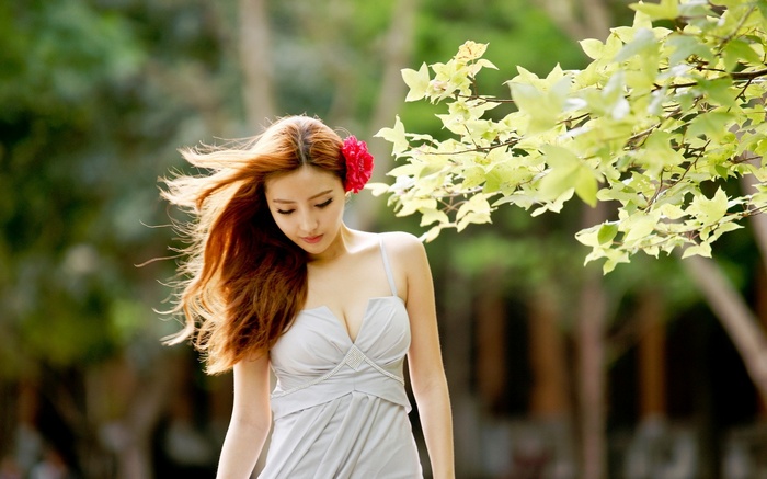 Asian woman with red flower in hair outdoors