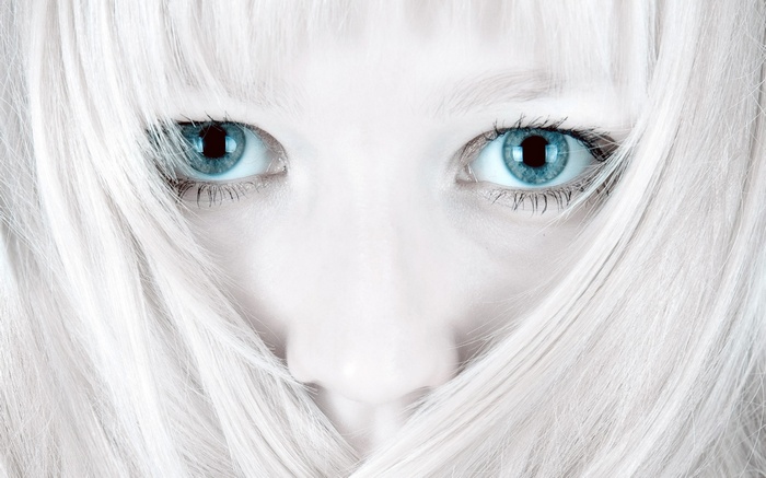 Close-up of a pale person with bright blue eyes and white hair