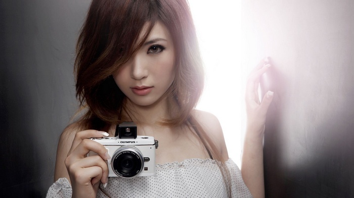 Asian woman holding an Olympus camera