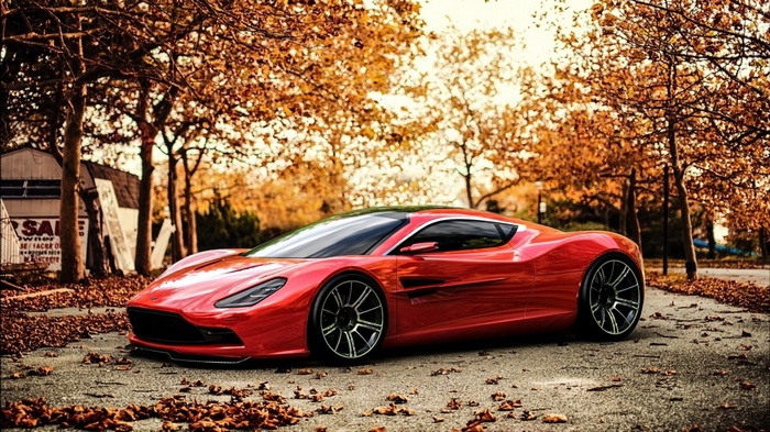 Red sports car parked on a leaf-covered road