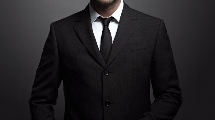 Man in a black pinstripe suit and tie