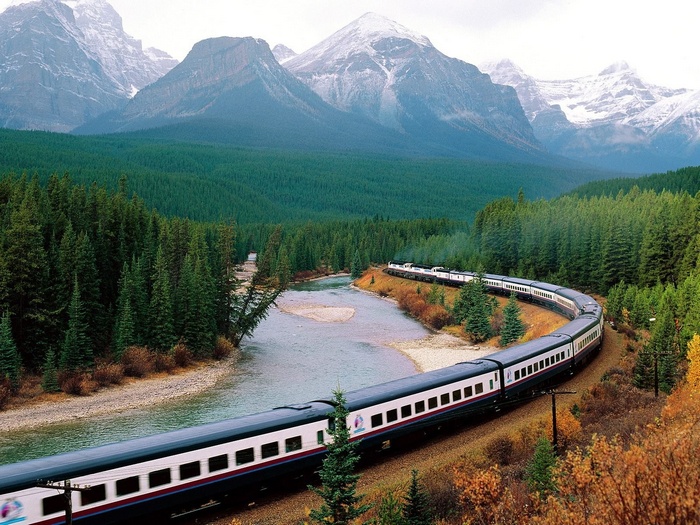 Train traveling through a Canadian mountain landscape with a river