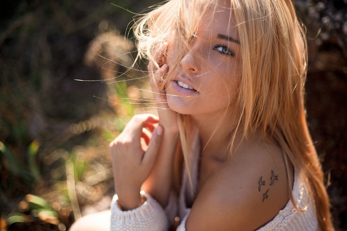 Woman with blonde hair and bird tattoo outdoors