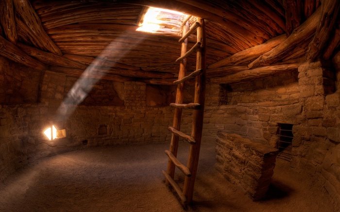 Interior of a stone structure with a wooden ladder and sunlight