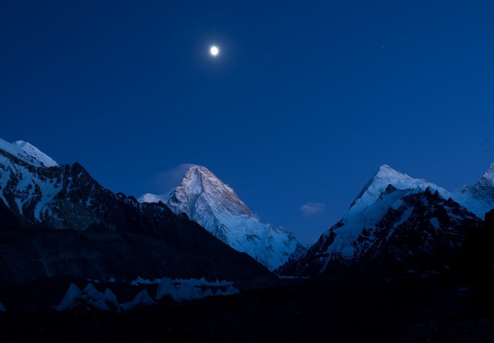 Moonlit mountains under a dark blue sky