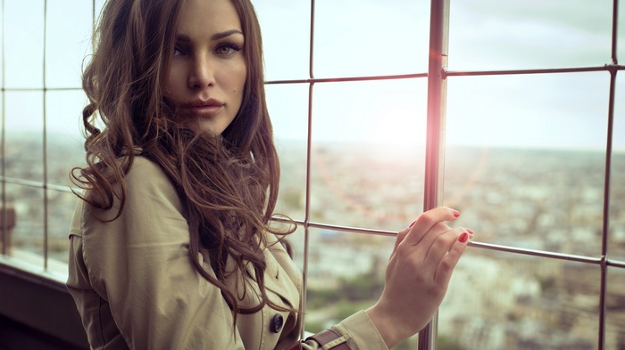 Woman in trench coat looking out window