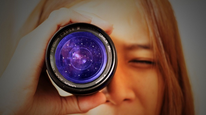 Woman looking through a Canon camera lens at stars