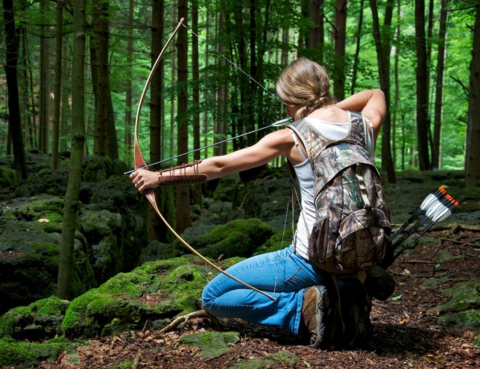 Woman practicing archery in a forest