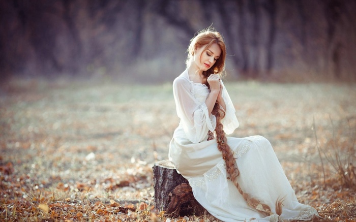 Woman with long braids in a white dress outdoors