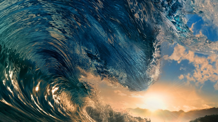 Ocean wave crashing at sunset with sunlight