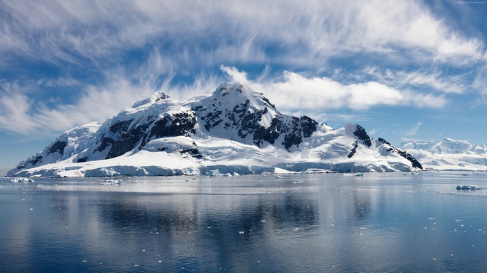 Snow-covered mountains and sea under a cloudy sky