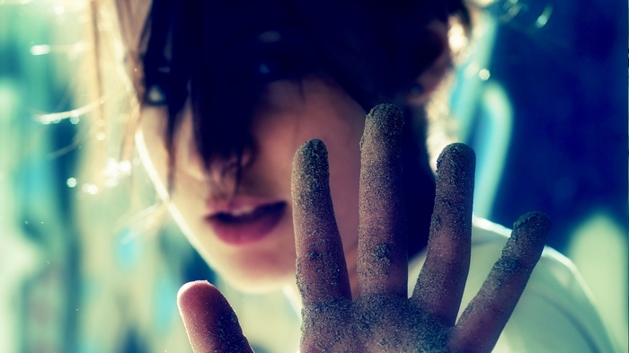 A person's hand covered in sand in front of their face