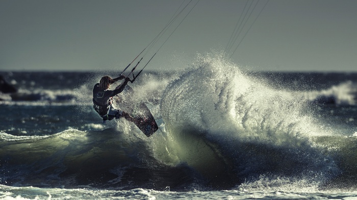 Kite surfer jumps over a large wave