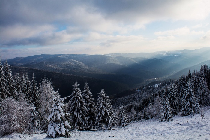 Winter mountain landscape with sun rays through clouds
