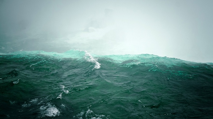 Dark green ocean waves under a misty sky