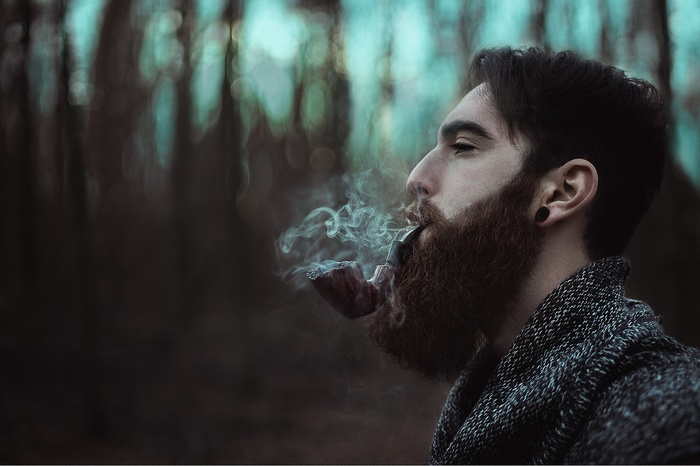 Man with beard smoking a pipe outdoors