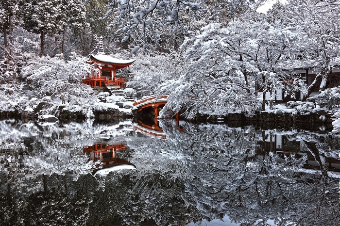 Snow-covered Japanese pagoda reflected in a pond