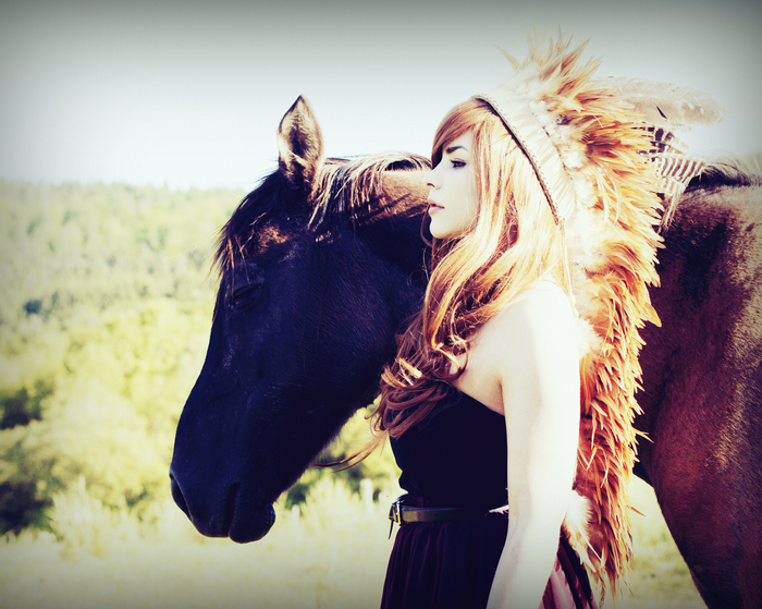 Woman with headdress and horse in a field