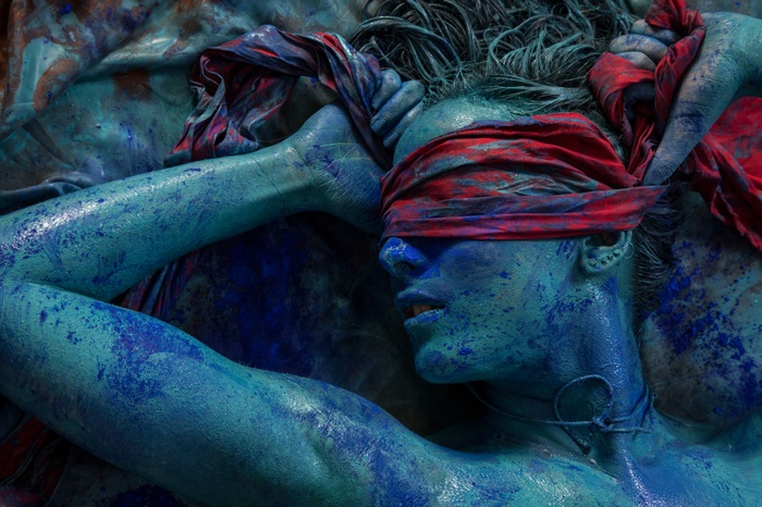 Woman covered in blue body paint with red blindfold