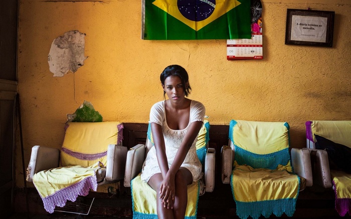 Woman in white dress in front of Brazil flag