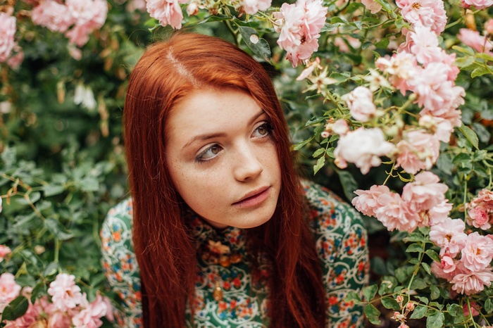 Redhead woman surrounded by pink roses