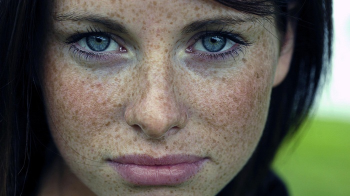 Close-up portrait of a woman with freckles and blue eyes