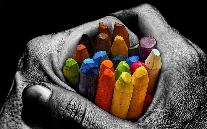 Hand holding colorful crayons with selective coloring