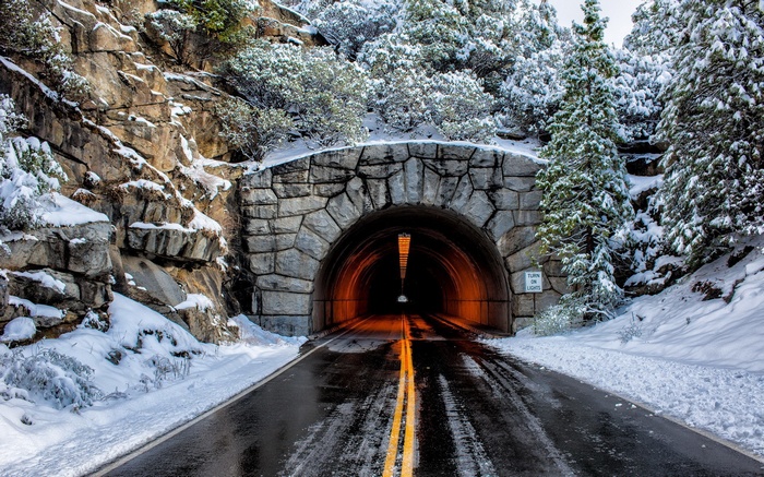 Snowy mountain tunnel entrance with a wet road