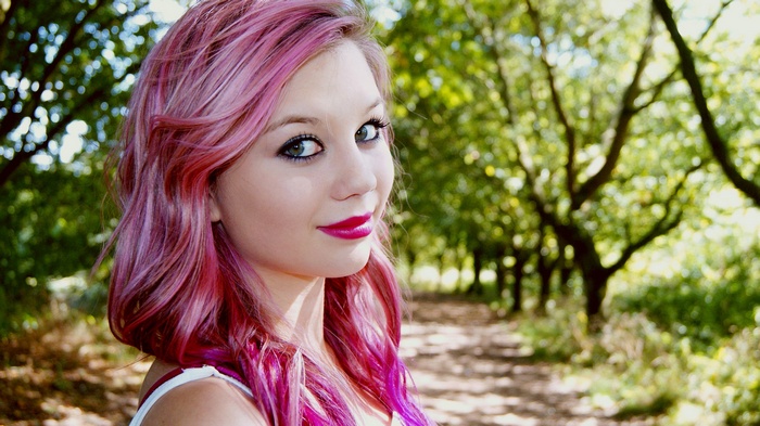 Woman with pink dyed hair in a forest path