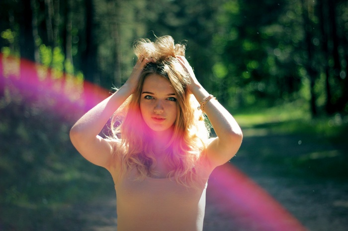 Blonde woman with hands in hair in a forest