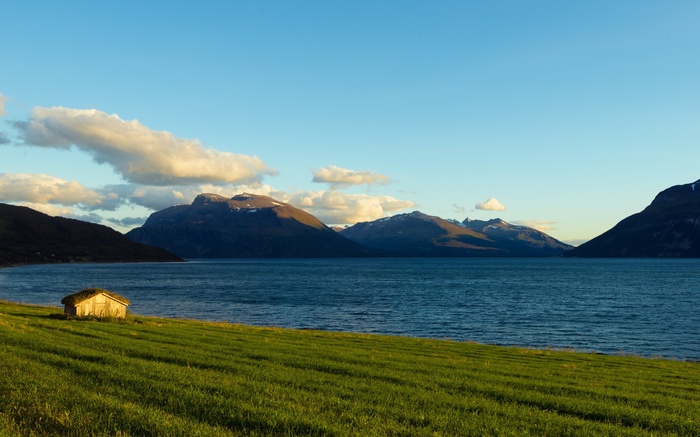 Small house on a grassy field by the sea in Norway