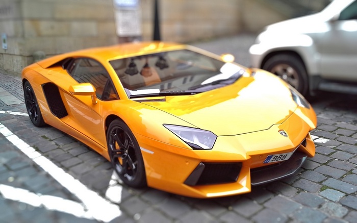 Orange Lamborghini Aventador parked on cobblestone street