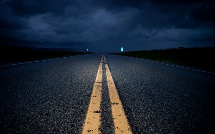 Empty highway at night under dark clouds