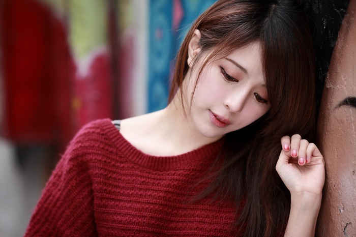 Asian woman with auburn hair wearing a red sweater