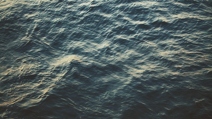 Dark blue ocean waves with sunlight reflections